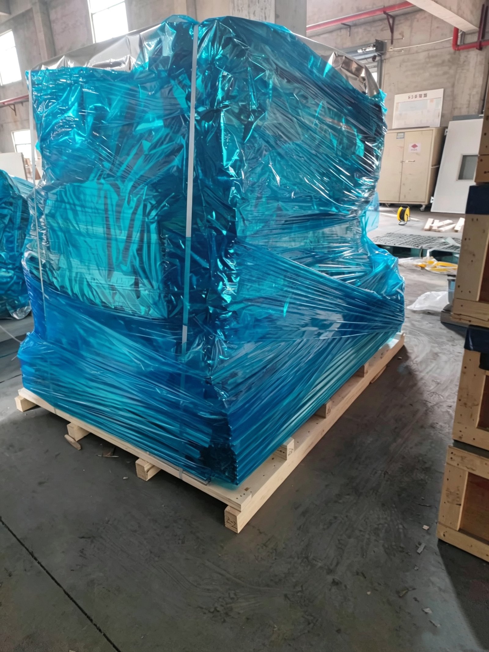 Industrial equipment wrapped in blue protective film on an export pallet.